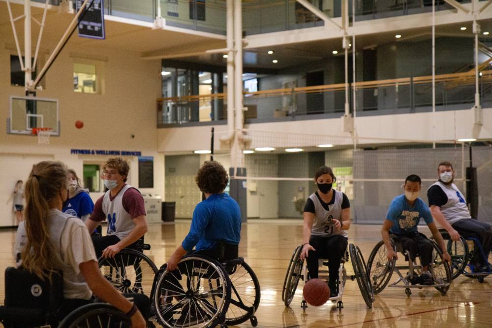 Woman dribbling a basketball in a wheelchair basketball game.